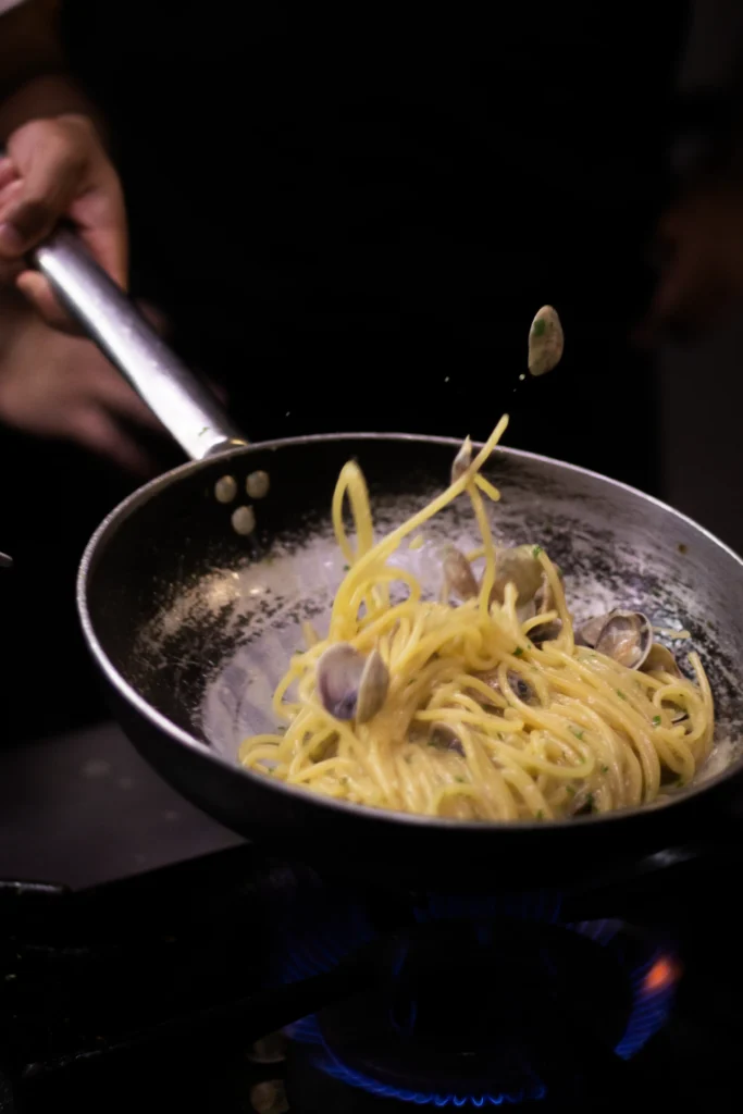 Chef prepara spaghetti alle vongole in padella, homepage Cantinone Storico Venezia